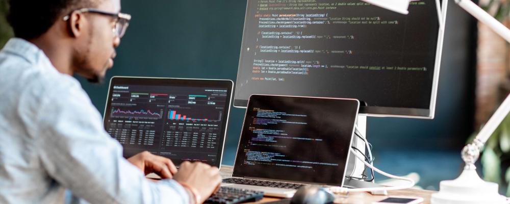 Software developer looking at computer with code on screen