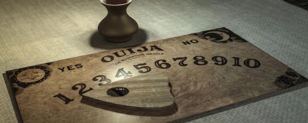 Ouija board with planchette and a small vase on a table, dimly lit.