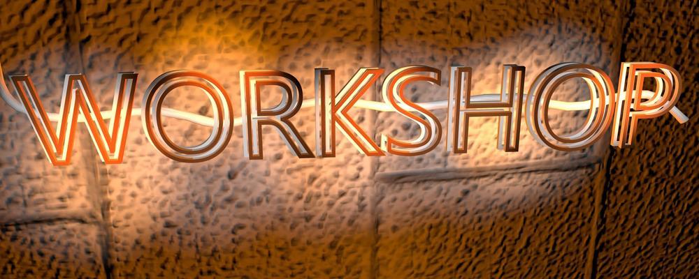 WORKSHOP text in glowing orange neon on a textured brown wall.
