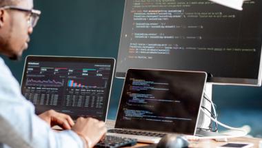 Software developer looking at computer with code on screen