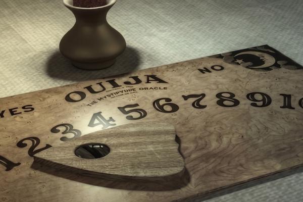 Ouija board with planchette pointing to numbers, dark vase in background.